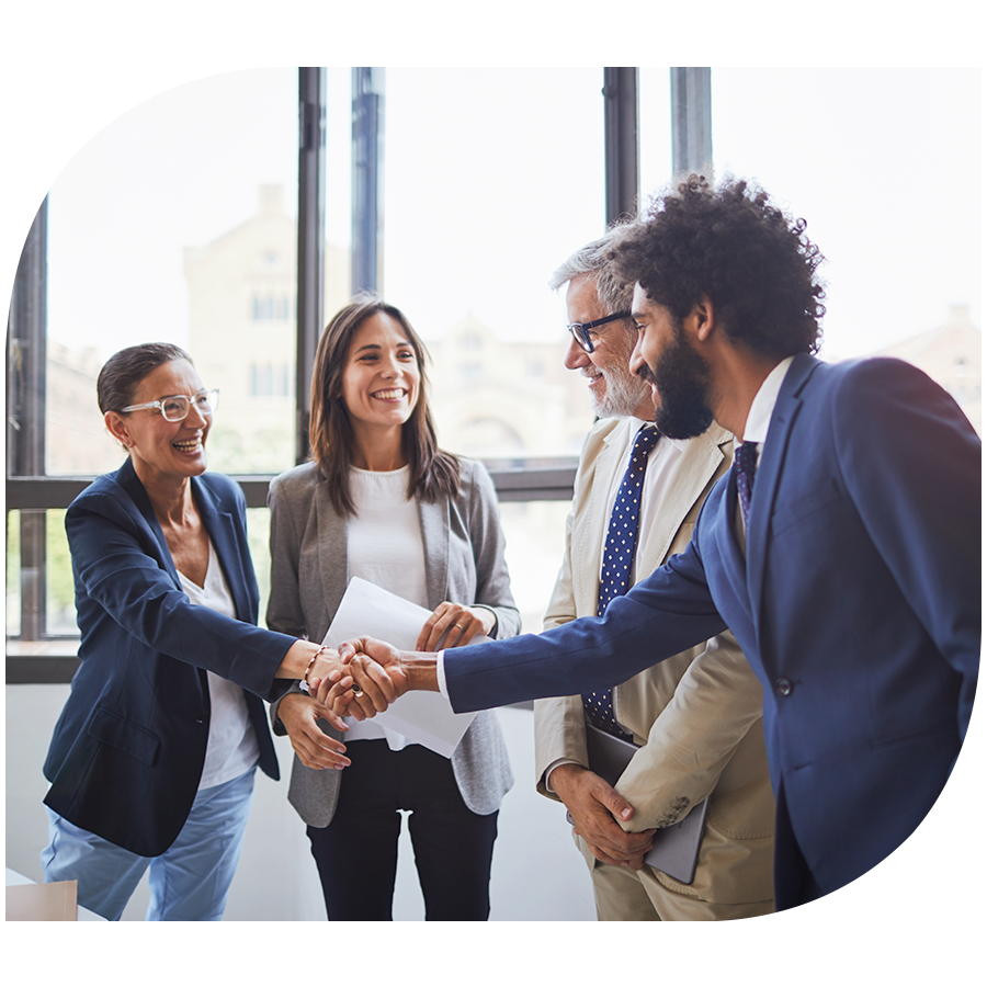 Two women and two men cheerfully shaking hands during a business meeting